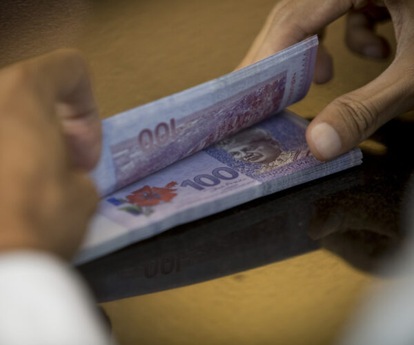 Malaysian Ringgits And Stock Boards Inside RHB Investment Bank Malaysian ringgit banknotes are counted in an arranged photograph at the RHB Investment Bank Bhd. headquarters in Kuala Lumpur, Malaysia, on Sunday, July 21, 2014. Photographer: Brent Lewin/Bloomberg